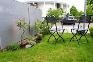 Die kleine Sitzgruppe und das Beet entlang des Müllhäuschens