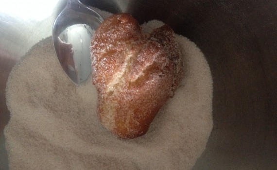 Krapfen in Zimt und Zucker wälzen